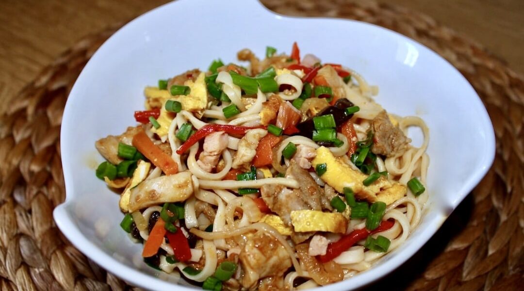 Bami Goreng to makaron wymieszany ze smażonymi kawałkami kurczaka, cebulą oraz warzywami, szynką i siekanym omletem.