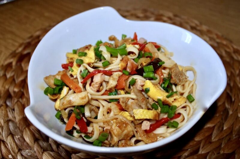 Bami Goreng to makaron wymieszany ze smażonymi kawałkami kurczaka, cebulą oraz warzywami, szynką i siekanym omletem.