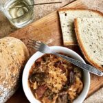 Tradycyjny bigos myśliwski z dziczyzną przygotowany z kapusty kiszonej z dodatkiem kilku rodzajów mięs, suszonych śliwek, grzybów i polskiej żubrówki dla smaku.