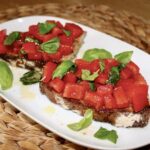 Bruschetta z pomidorami to grillowana i polana obficie oliwą kromka wiejskiego chleba z pomidorami, świeżą bazylią i solą morską.