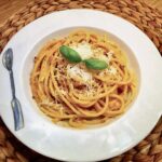 Makaron bucatini alla trapanese podany z pesto przyrządzonym z migdałów, pomidorków koktajlowych, sera pecorino i świeżej bazylii.