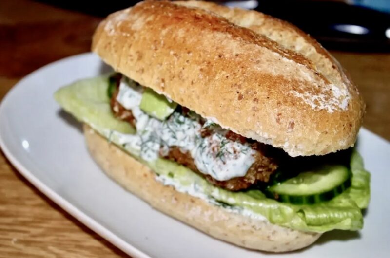 Burger z dorszem smażonym w panierce podany w bułce z dodatkiem awokado i chilli oraz z sosem koperkowym.