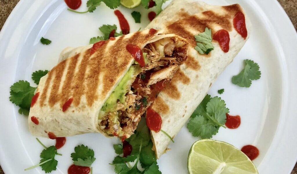Burrito z kurczakiem to duża tortilla wypełniona smażonym kurczakiem z dodatkiem startego sera, awokado, kolendry i salsy pomidorowej, a następnie zawinięta i podgrzana na patelni.