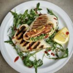 Burrito z tuńczykiem to duża tortilla wypełniona sałatką meksykańską z tuńczykiem oraz pomidorem, rukolą i awokado, zwinięta jak krokiet i podpiekana na grillu.