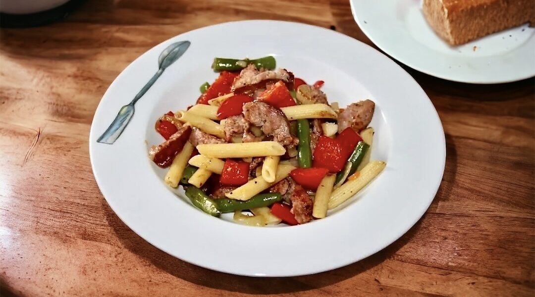 Chłopskie jadło to sycący posiłek przygotowany z makaronu z dodatkiem przesmażonych na cebuli kawałków kiełbasy oraz z fasolką szparagową i świeżą papryką.