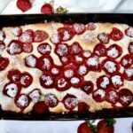 Puszyste ciasto drożdżowe z dojrzałymi słodkimi truskawkami posypane po upieczeniu cukrem pudrem.