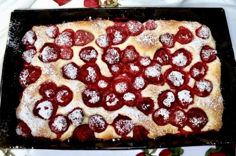 Puszyste ciasto drożdżowe z dojrzałymi słodkimi truskawkami posypane po upieczeniu cukrem pudrem.