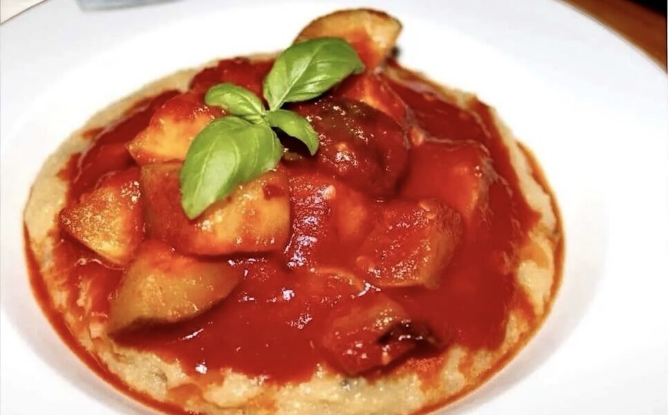 Cukinia pokrojona w kostkę i duszona z czosnkiem w pomidorach podawana z polentą z grzybami.