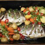 Dorada uprzednio marynowana w oliwie z dodatkiem soli, czosnku i rozmarynu, a następnie pieczona z dodatkiem podgotowanych warzyw.