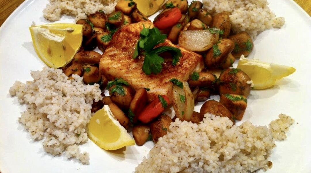 Dorsz pieczony podany z duszonymi warzywami korzeniowymi i pieczarkami.