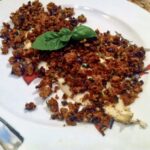 Dorsz filet przygotowany z kruszonką z czerstwego pieczywa, oliwek i suszonych pomidorów.