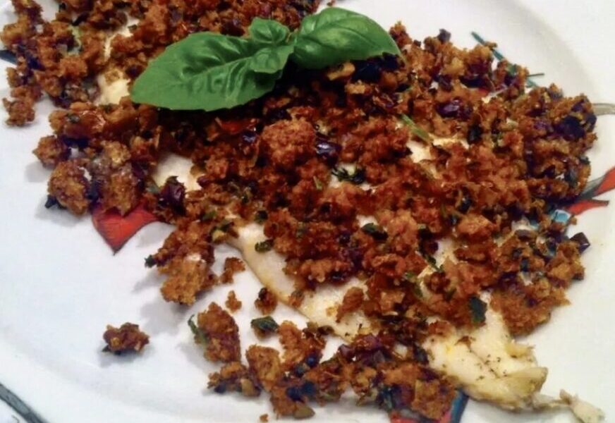 Dorsz filet przygotowany z kruszonką z czerstwego pieczywa, oliwek i suszonych pomidorów.