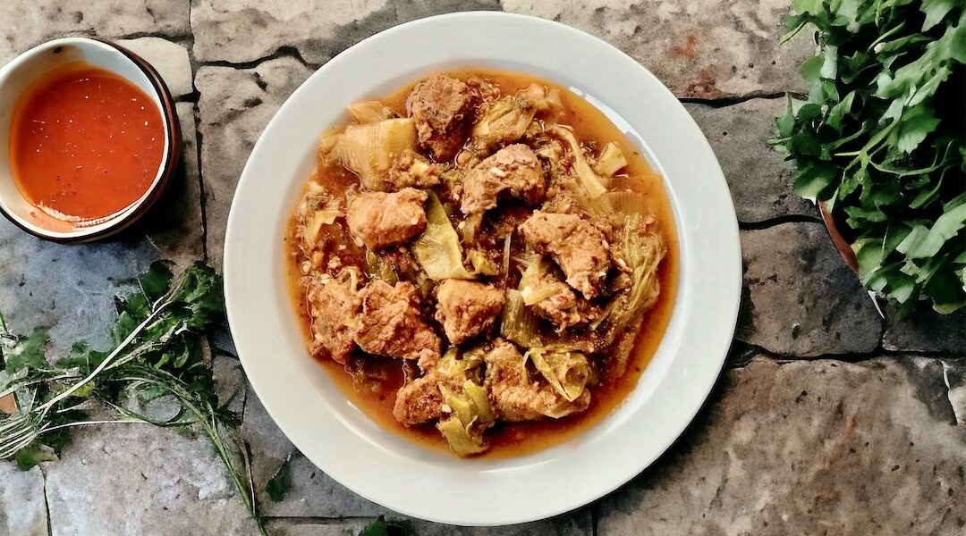 Wieprzowina duszona razem z czosnkiem, dymką i porami ze startymi pomidorami w przyprawach.