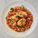 Kurze udka najpierw krótko smażone z cebulą i selerem naciowym, a następnie duszone razem z fasolką w pomidorach.