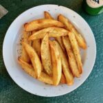 Frytki greckie to wykrojone z dużych podłużnych ziemniaków ósemki smażone w oliwie i na koniec sypane solą morską i oregano.