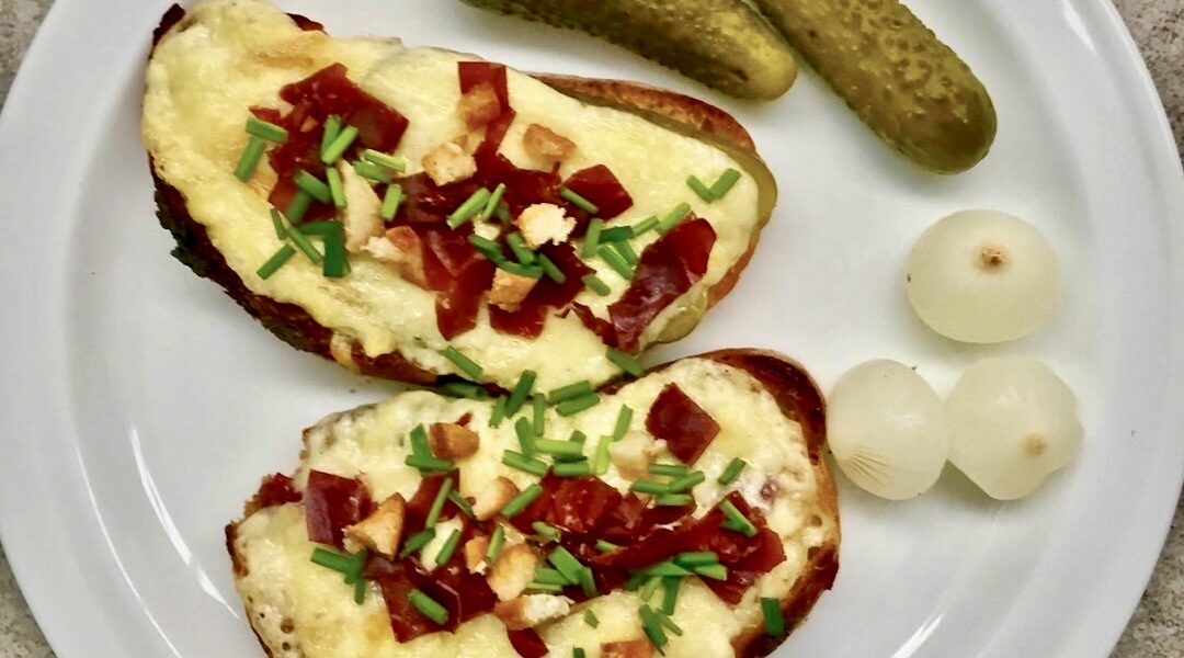 Grzanki ze stopionym serem raclette z dodatkiem suszonej wołowiny oraz korniszonów i cebulek marynowanych.