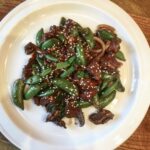 Jagnięcina pokrojona na małe kawałki marynowana w sosie sojowym i oleju sezamowym, a następnie smażona z imbirem, czosnkiem i dymką podawana z groszkiem cukrowym.