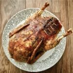 Świeża kaczka natarta suszonym majerankiem i wypełniona jabłkami a następnie pieczona.