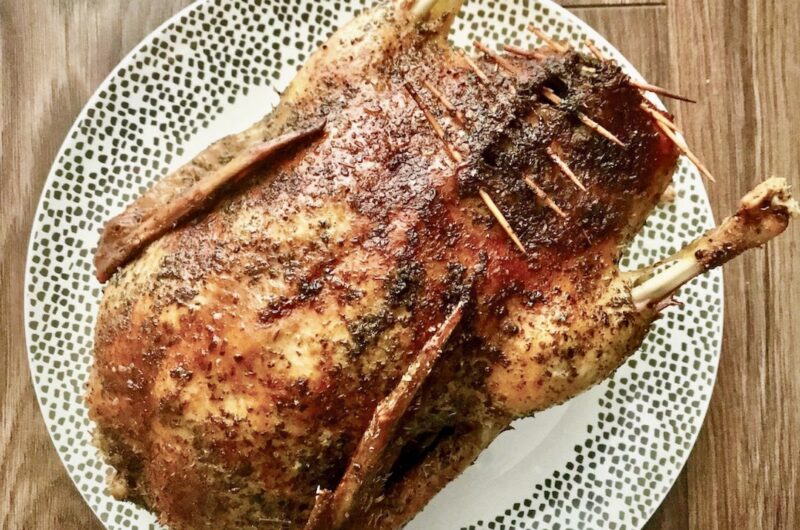 Świeża kaczka natarta suszonym majerankiem i wypełniona jabłkami a następnie pieczona.