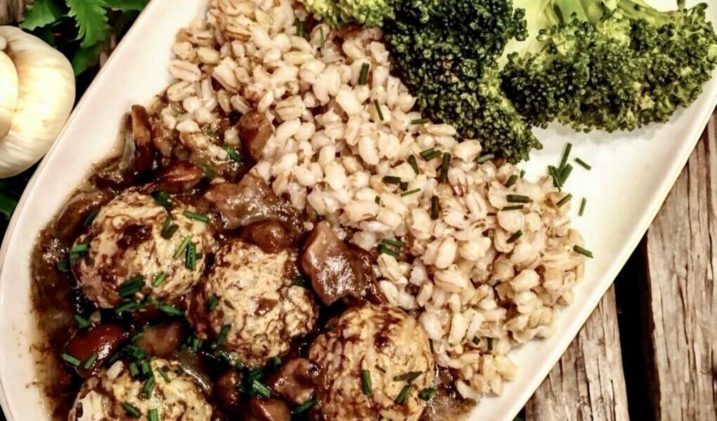 Klopsy cielęce z mięsa mielonego oraz ryżu, gotowane w bulionie warzywnym i podane w sosie grzybowym doprawionym kwaśną śmietaną.