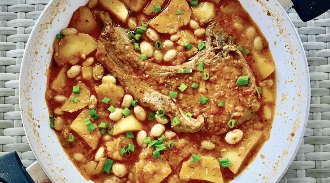 Kotlet schabowy smażony, a potem duszony z cebulą, czosnkiem, ziemniakami i fasolką.