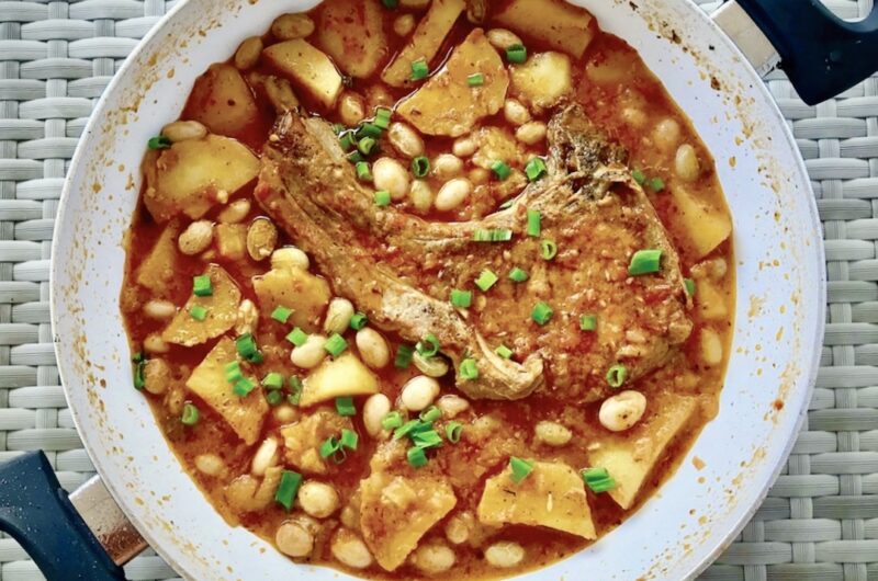 Kotlet schabowy smażony, a potem duszony z cebulą, czosnkiem, ziemniakami i fasolką.