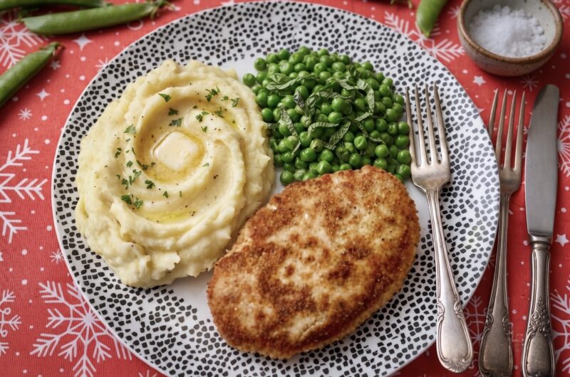 kotlet pożarski na talerzu podany z ziemniakami puree oraz groszkiem zielonym z masłem