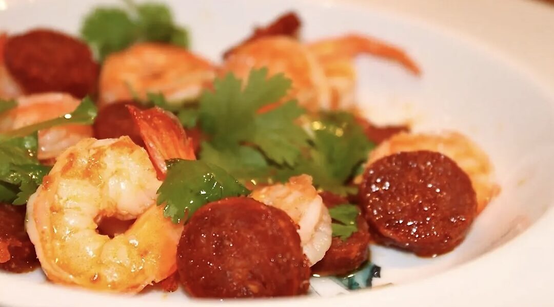 Krewetki smażone z czosnkiem razem z plastrami paprykowanej kiełbasy chorizo podane ze świeżą kolendrą.