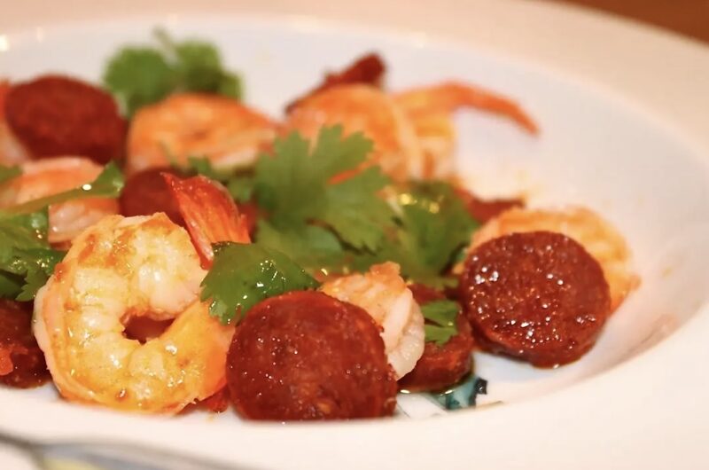 Krewetki smażone z czosnkiem razem z plastrami paprykowanej kiełbasy chorizo podane ze świeżą kolendrą.