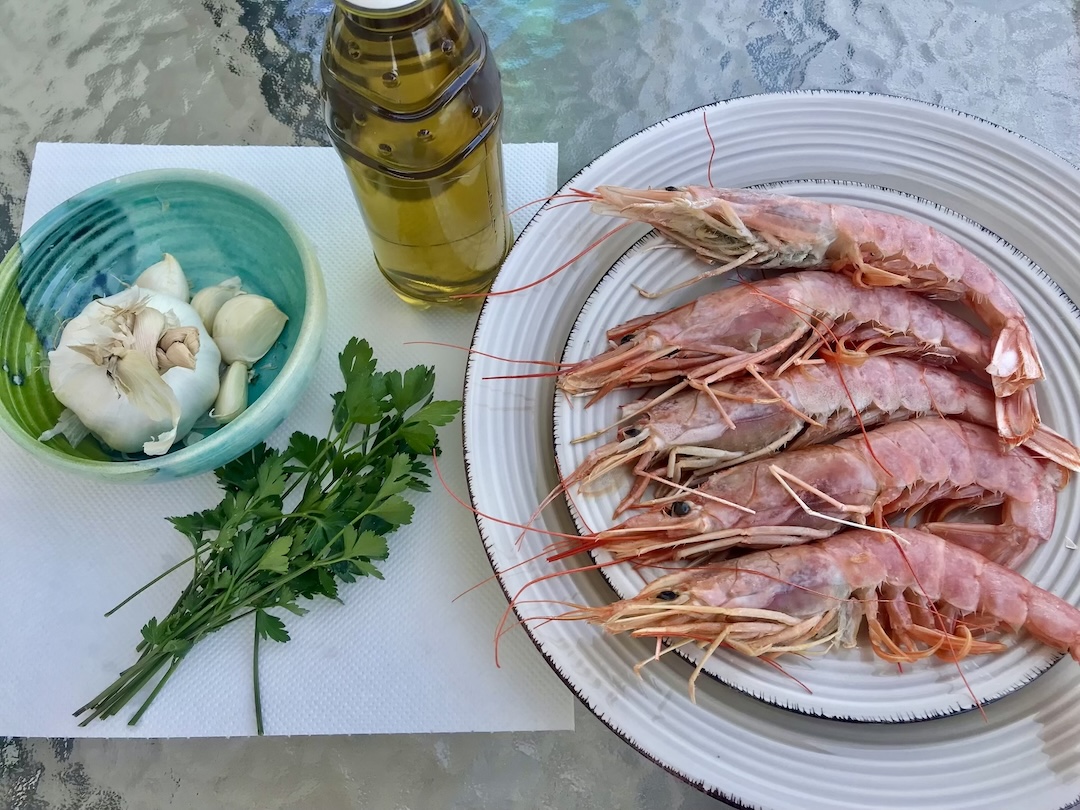 świeże krewetki leżą na talerzu obok czosnek i natka pietruszki