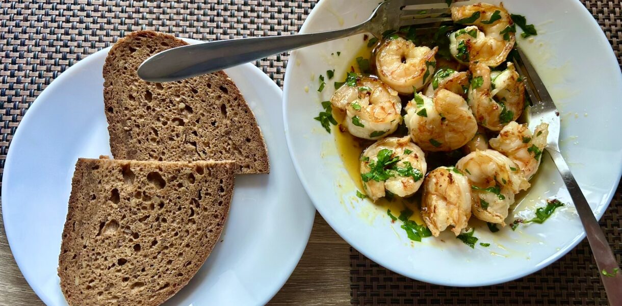 krewetki z czosnkiem na talerzu oraz dwie kromki ciemnego chleba