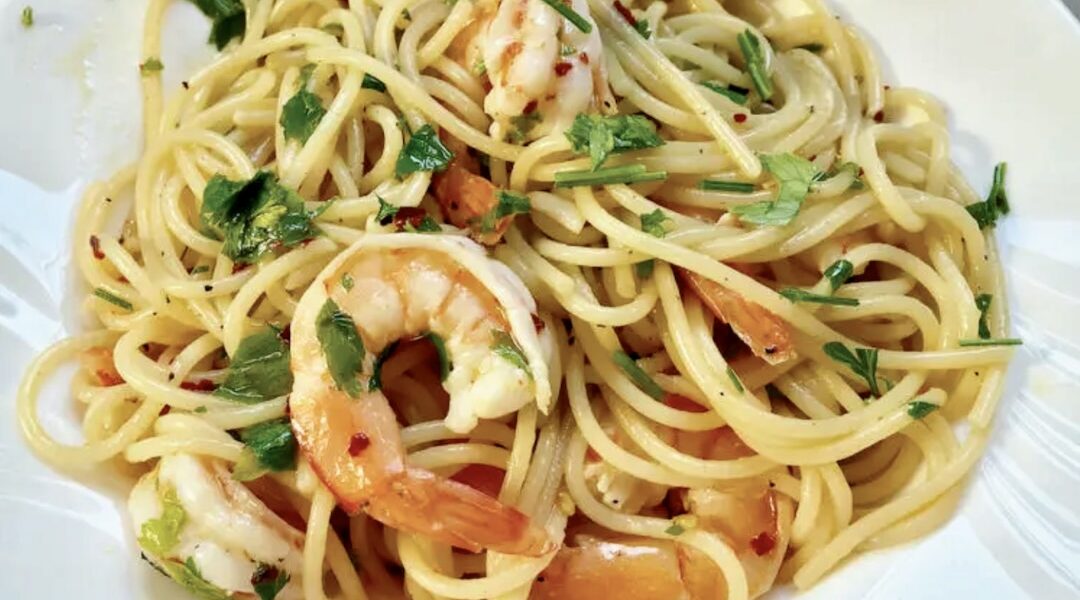 Krewetki smażone na oliwie z dodatkiem soku z cytryny, czosnku i natki pietruszki podane z makaronem spaghetti.