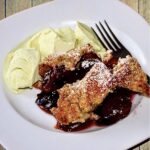 Kruszonka z masła, mąki i bakalii zapiekana ze śliwkami z sokiem z pomarańczy i cynamonem, pieczona i podane z lodami pistacjowymi.