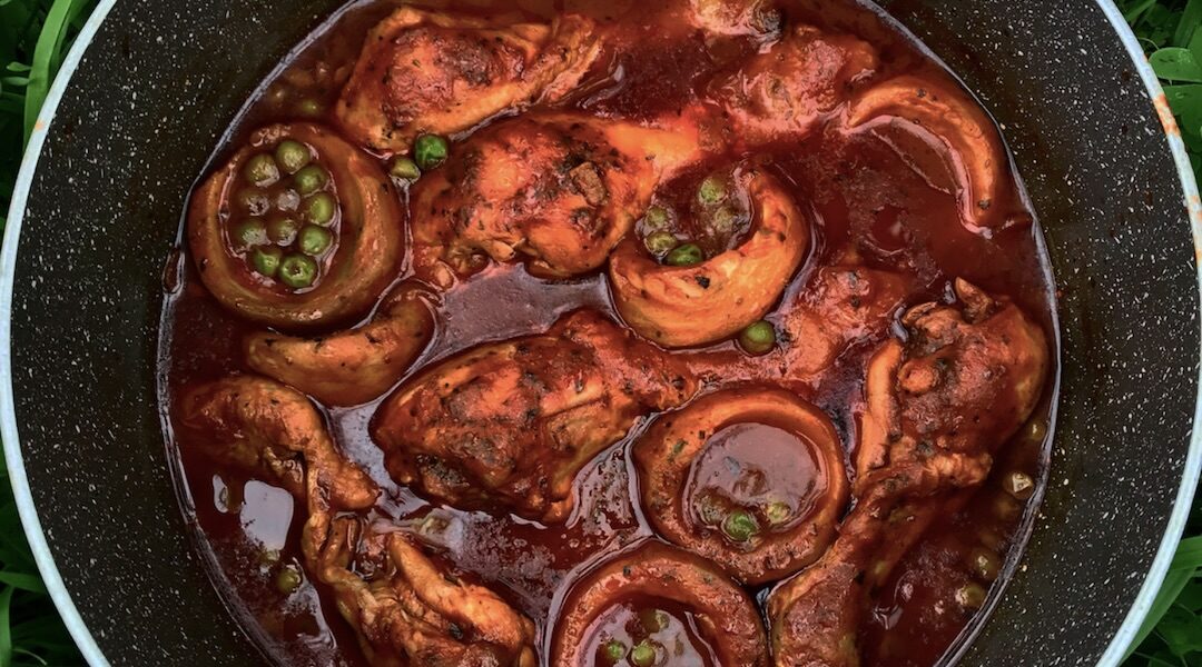 Kurczak w postaci podudzi duszony w sosie pomidorowym z karczochami i zielonym groszkiem doprawiony suszonym oregano.