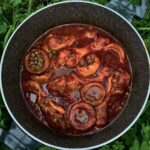 Kurczak w postaci podudzi duszony w sosie pomidorowym z karczochami i zielonym groszkiem doprawiony suszonym oregano.