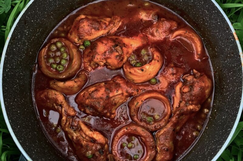 Kurczak w postaci podudzi duszony w sosie pomidorowym z karczochami i zielonym groszkiem doprawiony suszonym oregano.