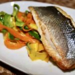 Labraks filet krótko smażony i podany z warzywami w postaci tagliatelle z cukinii i marchewki z dodatkiem czosnku i chili.