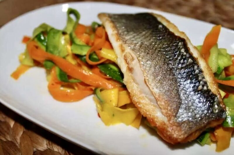 Labraks filet krótko smażony i podany z warzywami w postaci tagliatelle z cukinii i marchewki z dodatkiem czosnku i chili.