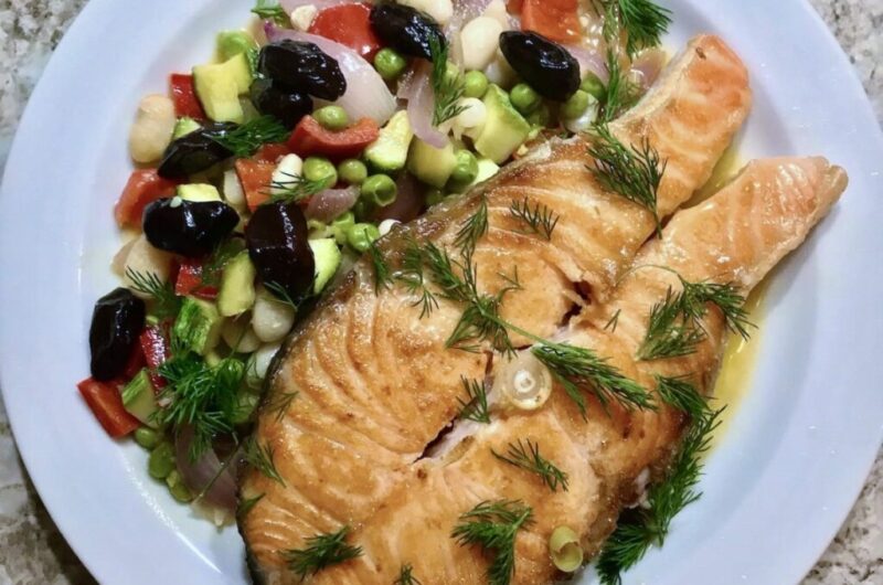 Łosoś smażony podany z sałatką z białej fasolki i groszku z dodatkiem drobno krojonych i smażonych cukinii, papryki i cebuli.