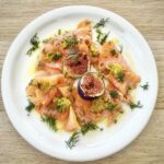 Łosoś wędzony w plastrach podany z dojrzałymi figami i sosem musztardowym, na koniec skropiony oliwą.