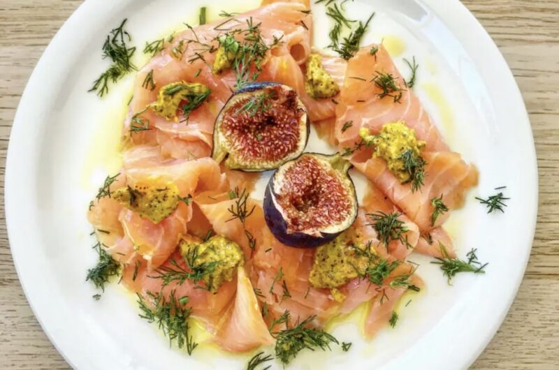 Łosoś wędzony w plastrach podany z dojrzałymi figami i sosem musztardowym, na koniec skropiony oliwą.