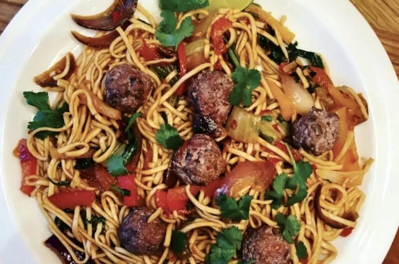 Makaron przyrządzony po chińsku podany z krojonymi i smażone warzywami w ostrym sosie podany z klopsikami jagnięcymi i z dodatkiem świeżej kolendry.