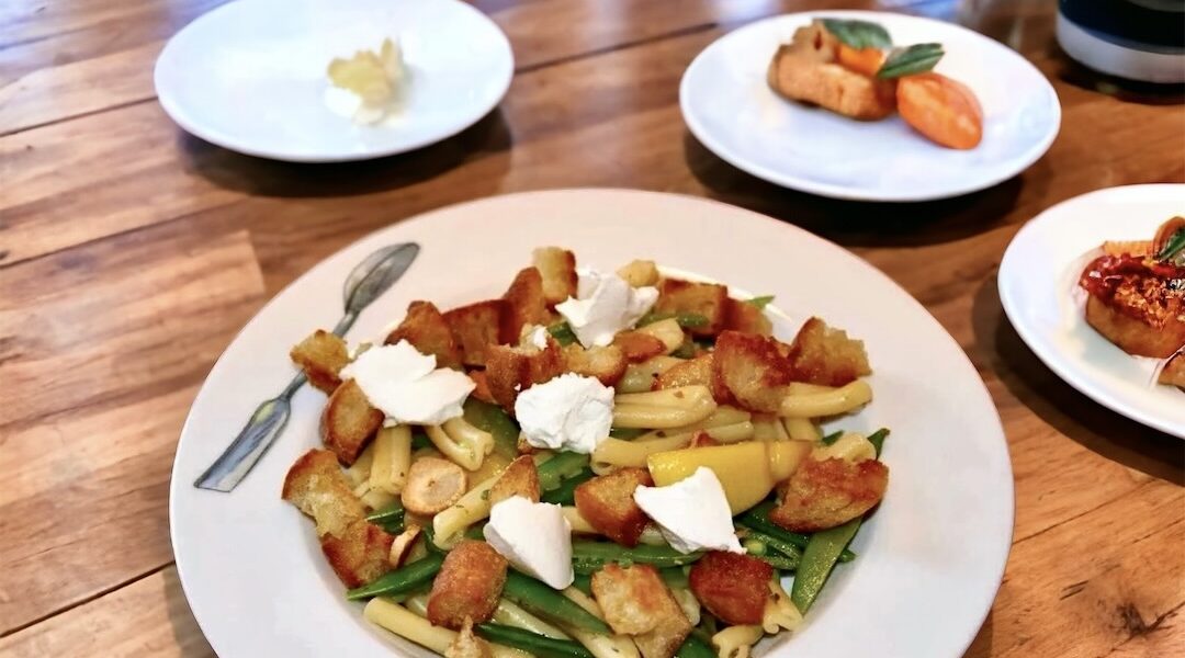 Makaron zmieszany z groszkiem cukrowym w oliwie czosnkowej z cytryną, a następnie uzupełniony grzankami i kozim serem.