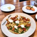 Makaron zmieszany z groszkiem cukrowym w oliwie czosnkowej z cytryną, a następnie uzupełniony grzankami i kozim serem.