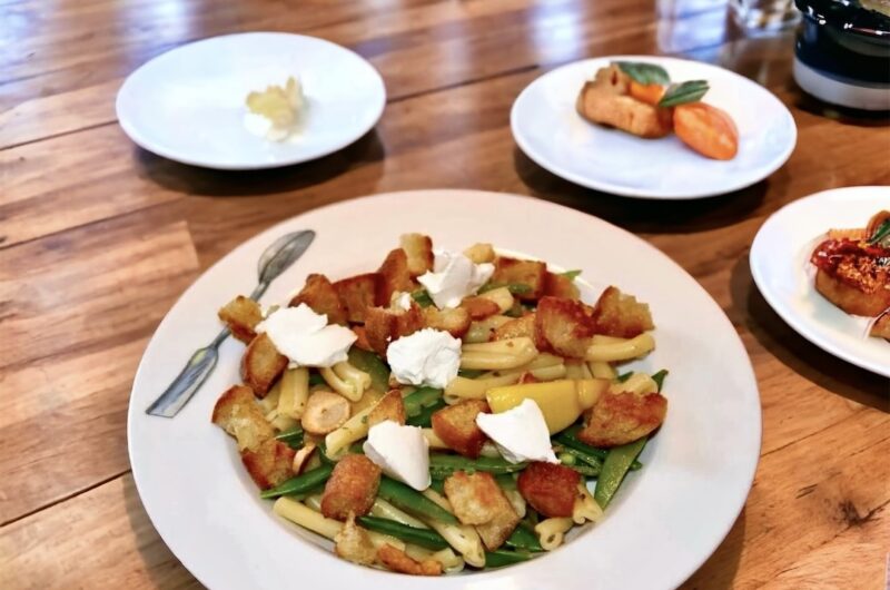 Makaron zmieszany z groszkiem cukrowym w oliwie czosnkowej z cytryną, a następnie uzupełniony grzankami i kozim serem.