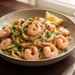 Krewetki smażone na oliwie z dodatkiem soku z cytryny, czosnku i natki pietruszki podane z makaronem spaghetti.