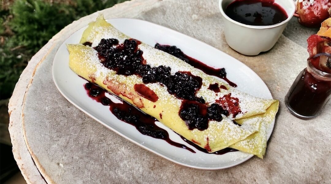 Naleśniki posmarowane dżemem z kawałkami owoców, następnie zwinięte w rulon i podane z owocami leśnymi.