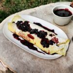 Naleśniki posmarowane dżemem z kawałkami owoców, następnie zwinięte w rulon i podane z owocami leśnymi.