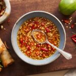 Sos Nuoc Cham przygotowuje się z papryczek chilli i świeżego czosnku z dodatkiem sosu rybnego, cukru, wody i soku z limonki.