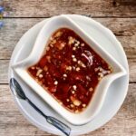 Sos Nuoc Cham przygotowuje się z papryczek chilli i świeżego czosnku z dodatkiem sosu rybnego, cukru, wody i soku z limonki.